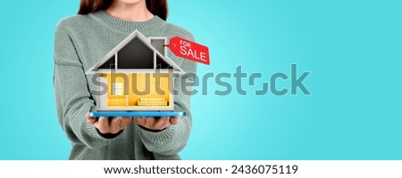 Woman hands with tablet and new small house, red tag for sale on empty colored background. Concept of real estate, buy a new apartment, relocation, agent and good offer