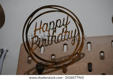 A round happy birthday sign attached to a board