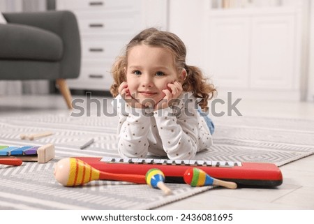 Little girl playing with toy musical instruments at home