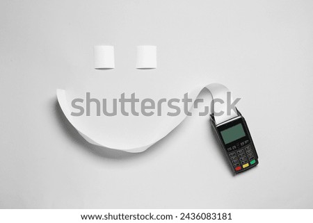 Payment terminal and smiling face made of thermal paper for receipt on light grey background, flat lay