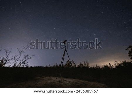 Landscape astrophotography, camera on a tripod against the backdrop of the starry sky in nature. 