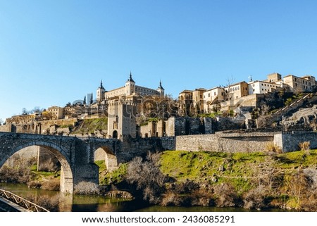 Toledo visto desde abajo, se puede apreciar el puente, el alcázar y el centro de la ciudad en un día despejado con el cielo azul Royalty-Free Stock Photo #2436085291