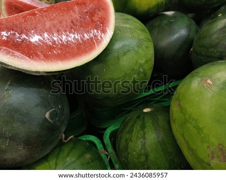 close up photo of a pile of fresh watermelons, the watermelons are in a basket