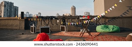 object photo of outdoor rooftop with vivid carpets and DJ equipment with red cups on table, banner