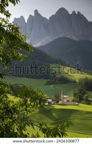 Vertical Santa Maddalena village in front of the Geisler or Odle Dolomites Group, Val di Funes, Trentino Alto Adige, Italy, Europe. Blue sky and green grass in Summer, August Royalty-Free Stock Photo #2436100877