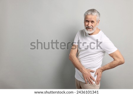 Arthritis symptoms. Man suffering from hip joint pain on gray background, space for text Royalty-Free Stock Photo #2436101341