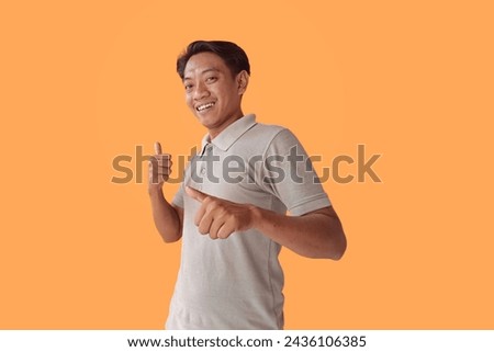 Handsome Asian man standing over orange background pointing fingers to camera with happy and funny face. good energy and vibes.