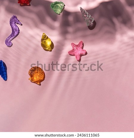 Marine transparent colorful figurines or kid's toys with under water texture light shadows on the pink background. Summer sea vacation concept composition. Copy space
