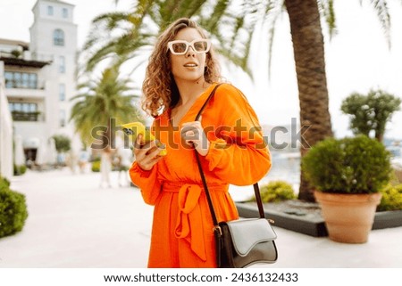 Portrait of beautiful woman in summer dress walking on the street with mobile phone. Lifestyle, travel, tourism, active life.