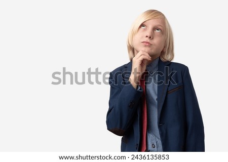 Thoughtful young man with short blond hair, dressed in blue jacket and red tie, looking up and thinking, isolated over white background Royalty-Free Stock Photo #2436135853