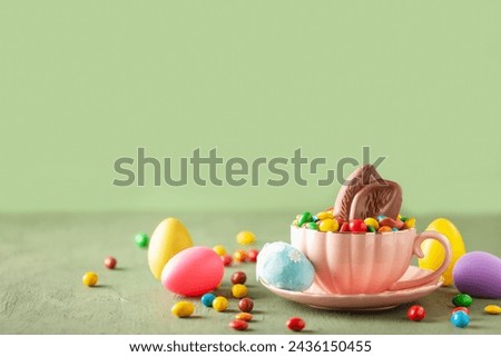 Rabbit chocolate ears and colored dragee sweets in a cup on the table. Easter concept. Copy space