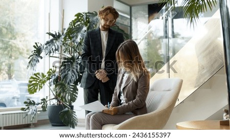 The director of a business woman signs contractual documents with her assistant. Business transaction, deal closing, financing costs and income.