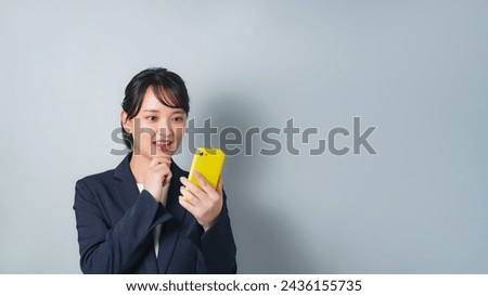 A woman wearing a business suit using a smartphone