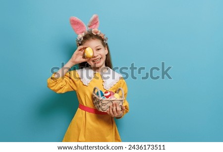 Cute little child wearing bunny ears on Easter day. Girl with painted eggs. Royalty-Free Stock Photo #2436173511