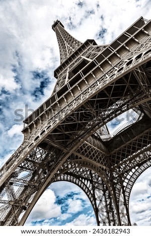 Eiffel Tower with blue sky and cloud background. Low angle view looking up. Built by engineer Gustave Eiffel, and opened in 1889. Champ de Mars, Paris, France.