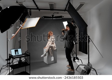 Model young woman preparing posing for photo taken with professional photographer in studio on fashion concept