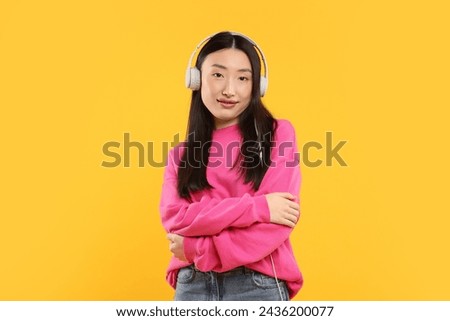 Portrait of beautiful woman in headphones on orange background