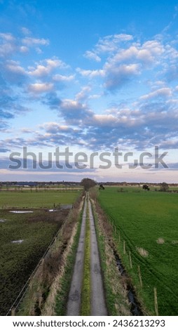 Country Road and Farmland Under a Cloud-Adorned Sky Country Road and Farmland Under a Cloud-Adorned Sky. High quality photo Royalty-Free Stock Photo #2436213293