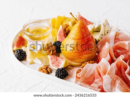 Italian antipasto with prosciutto, cheeses, nuts and fruits Royalty-Free Stock Photo #2436216533