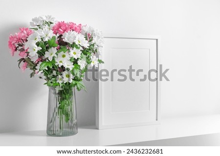 Blank portrait frame mockup in white interior with fresh flowers bouquet in vase, mockup with copy space