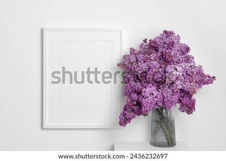 Landscape picture frame mockup on whte wall with fresh lilac flowers bouquet, blank mockup with copy space