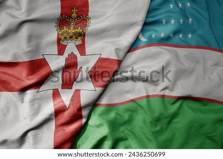 big waving national colorful flag of uzbekistan and national flag of northern ireland . macro