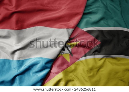 big waving national colorful flag of mozambique and national flag of luxembourg . macro