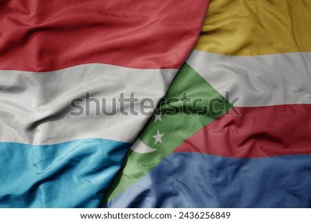 big waving national colorful flag of comoros and national flag of luxembourg . macro