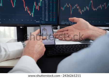 Cropped photo of exchange traders pointing lowest chart stage on dynamic graph with smartphone on hands focus, analyzing comparing with monitor and phone, discussing financial technology. Sellable.
