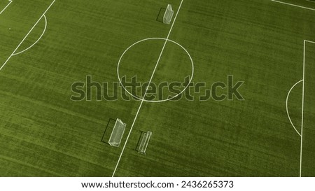 Aerial closeup of the midfield circle in an empty synthetic grass football field. Here the kick off is taken in a game of soccer.