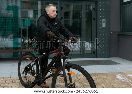 European elderly man leading a healthy lifestyle and riding a bicycle in winter