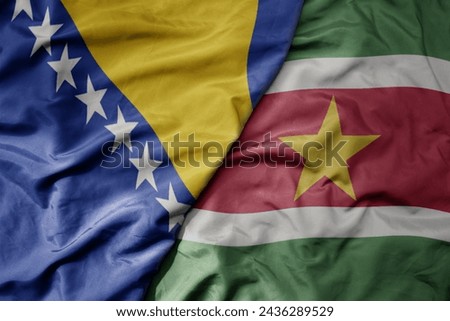 big waving national colorful flag of suriname and national flag of bosnia and herzegovina. macro