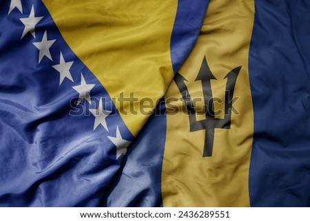 big waving national colorful flag of barbados and national flag of bosnia and herzegovina. macro
