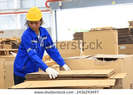 African american engineer woman wearing safety helmet and vest holding card box in the automotive part warehouse.Products and corrugated cardboard. Factory female worker in the manufacture of paper.