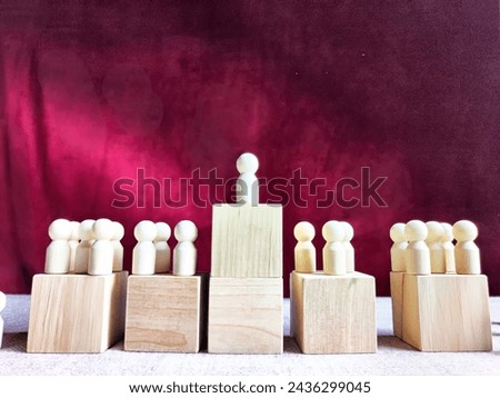 Wooden toy doll on high pedestal and many other figures below. Concept of leadership, which is not available to everyone. Victory and the winner. Talent, Recruitment employee and Successful business Royalty-Free Stock Photo #2436299045