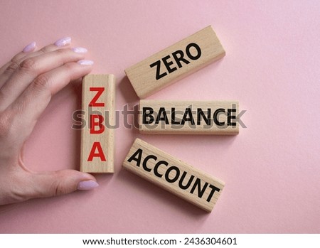 ZBA - Zero balance Account. Wooden cubes with word ZBA. Businessman hand. Beautiful pink background. Business and ZBA concept. Copy space.