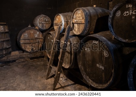 Aging process of cognac spirit in old dark French oak barrels in cellar in distillery house, Cognac white wine region, Charente, Segonzac, Grand Champagne, France Royalty-Free Stock Photo #2436320441
