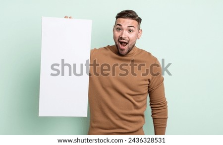 young handsome man looking very shocked or surprised. empty canvas concept