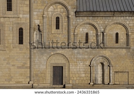 Background for design, texture walls and windows of houses, building facades. Georgia orthodox church, public places. arched Classic windows in granite exterior wall. small arched windows protected. 