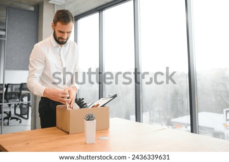 Sad Fired. Let Go Office Worker Packs His Belongings into Cardboard Box and Leaves Office. Workforce Reduction, Downsizing, Reorganization, Restructuring, Outsourcing. Mass Unemployment Market Crisis.
