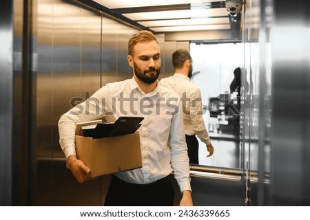 Man by dismissal. Guy lost job. Fired manager in company. Dismissal box in hands of employee. Man office worker disappointed by dismissal. Fired male in blurred office. Discharge company employees Royalty-Free Stock Photo #2436339665
