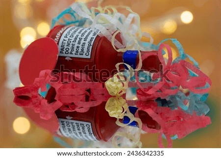 A macro closeup image of a party popper with its colourful paper streamers strewn across it. Reflected in a mirror lights in the background give it a Bokeh effect.