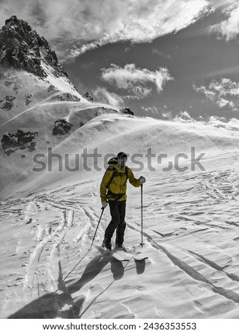 Black white ski touring picture. Young man on skis mountaineering in a fantastic mountain landscape in strong wind. Skitour in a strong storm. High quality photo