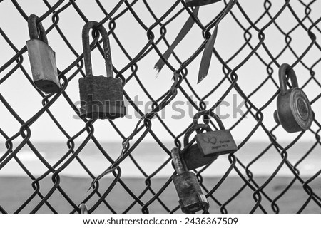 Black and white photo of locks symbolizing love attached to a fence in Asbury Park, NJ with the ocean in the background