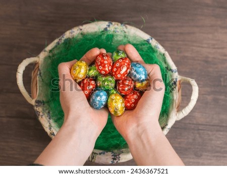 Woman hands holding a stack of coloured easter eggs