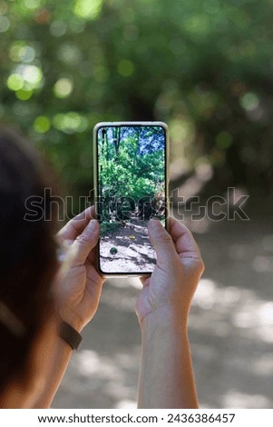 Woman taking a photograph of a landscape with her smartphone.