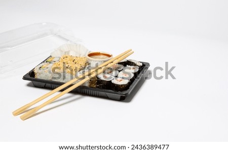 Sushi to go in a black takeaway box with wooden chopsticks on white background 