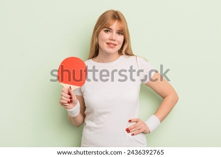 redhead pretty woman smiling happily with a hand on hip and confident. ping pong concept