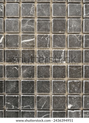 Gray ceramic tiles in mosaic pattern. Finishing material on exterior or interior bathroom wall. Abstract architecture detail. Checkered background with regular ormanent structure of squares.