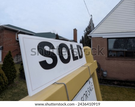 Sign sold in front of detached house in residential area. Real estate bubble, crash, hot housing market, overpriced property, buyer activity, interest rates rise concept. Selective focus.